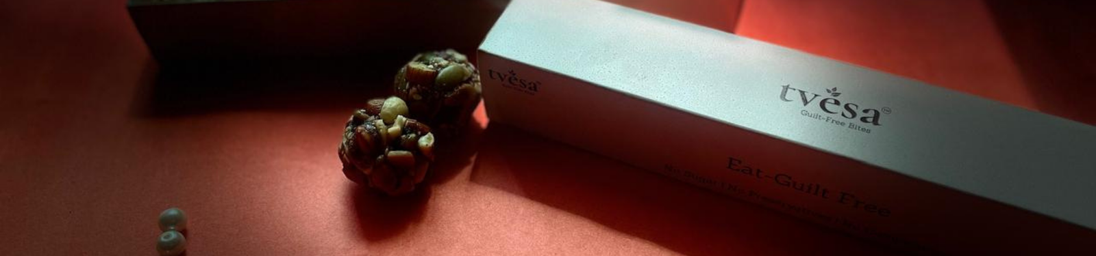 Tvesa ladoo box with healthy guilt-free sweets on a festive red background